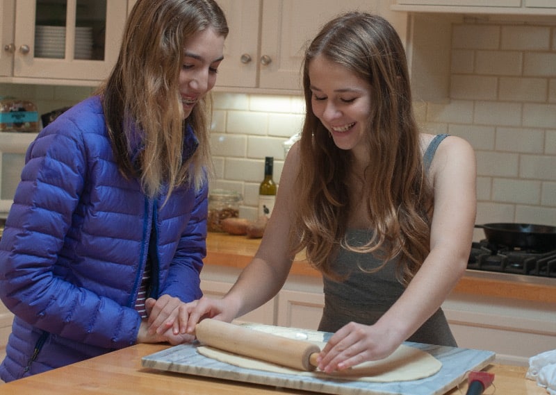 Zoe rolling out the pizza dough with a friend