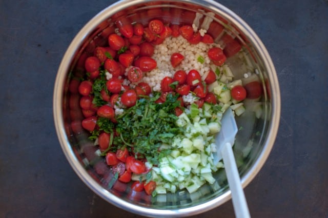 adding couscous cucumber and tomatoes in mixing bowl