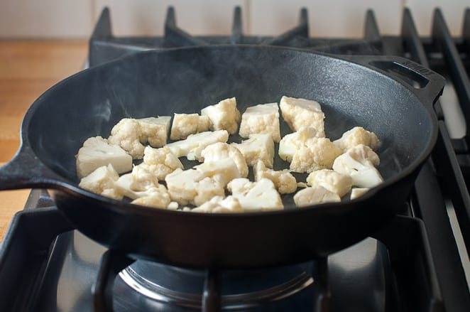 Cauliflower added to a hot skillet on the stove