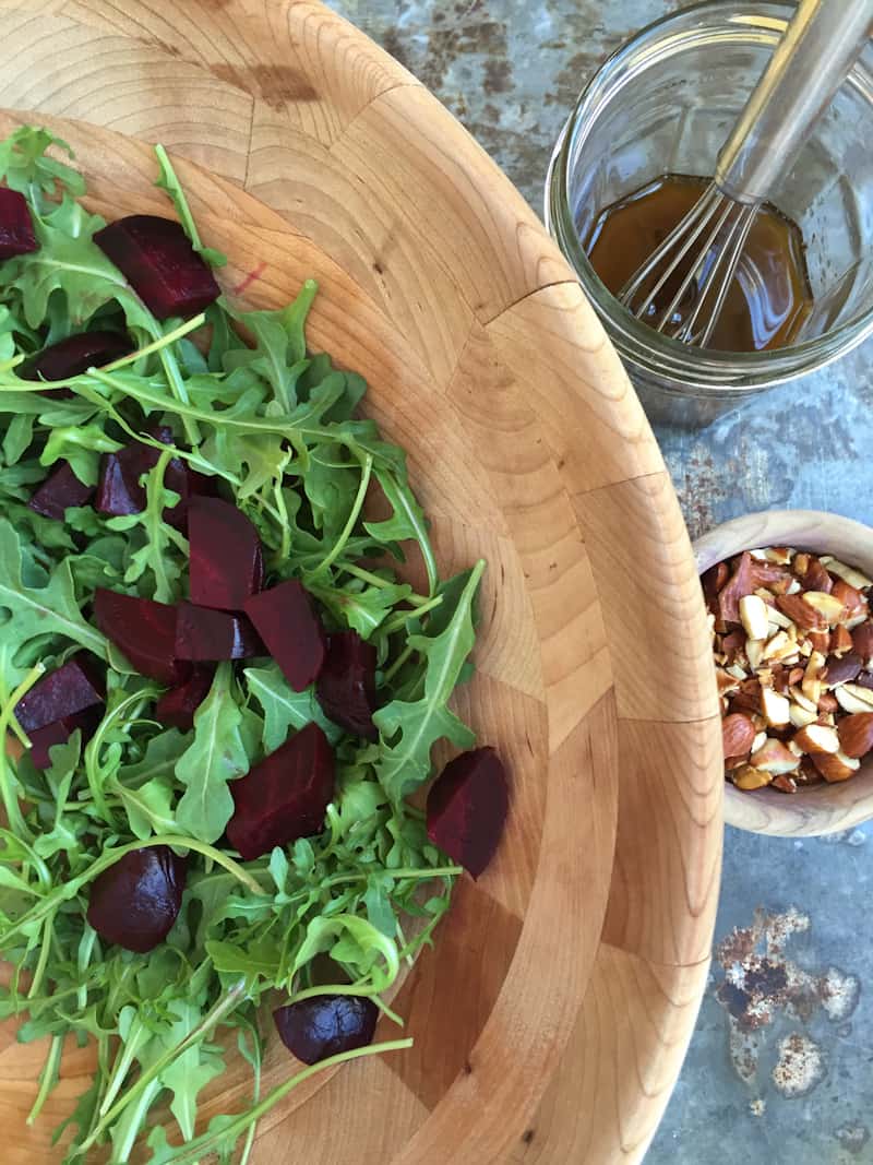 adding the roasted beets to the arugula