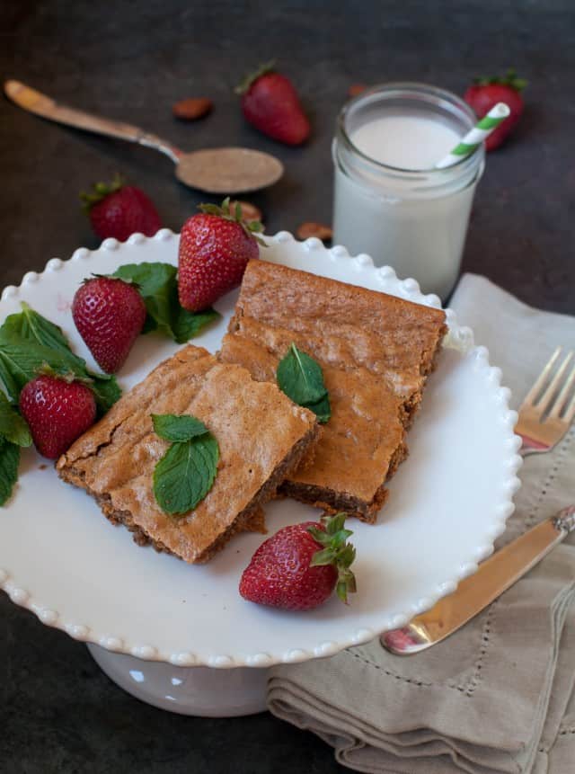 Almond butter brownies on the table with strawberries and a glass of milk