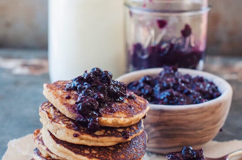 almond flour pancakes stacked with bowl of blueberry compote and jar of milk