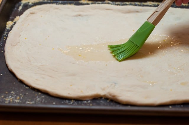 brushing oil onto the pizza dough