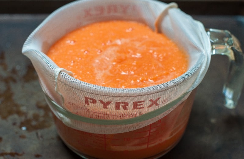 carrot juice in jelly bag in pyrex measuring cup