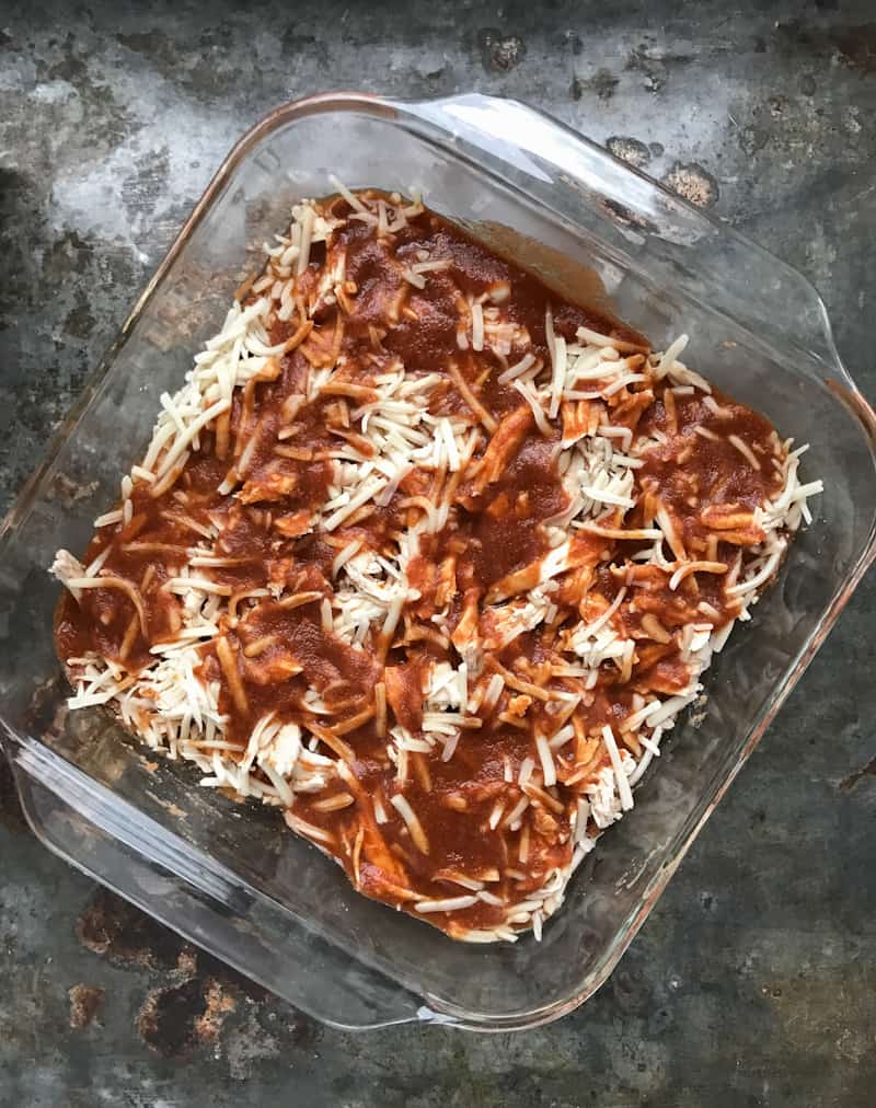 cheese and sauce layer in pan for chicken enchilada bake