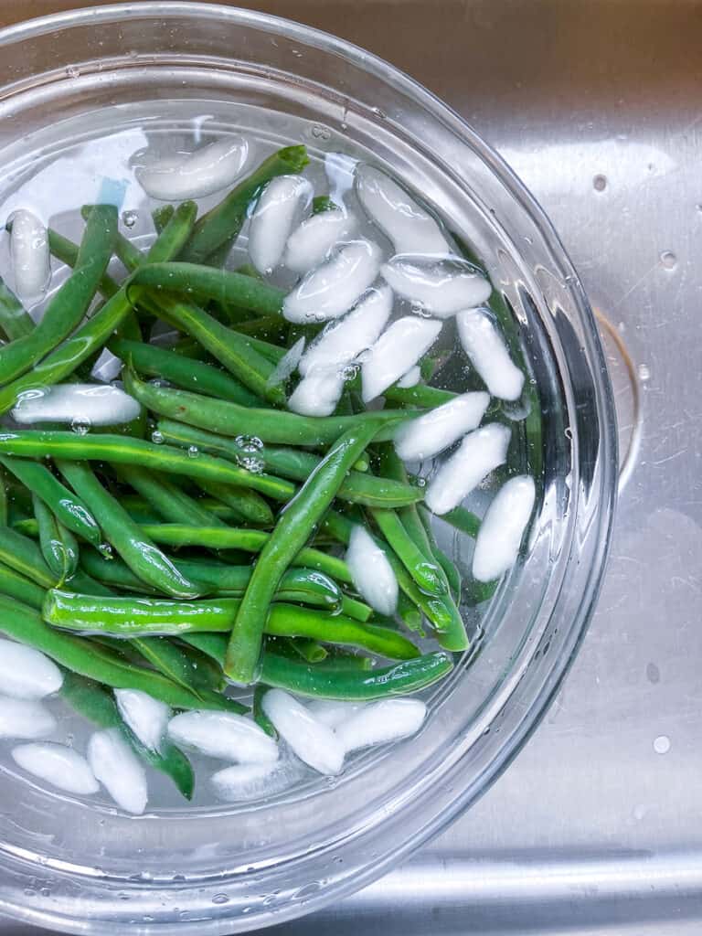 Blanched green beans in an ice bath.