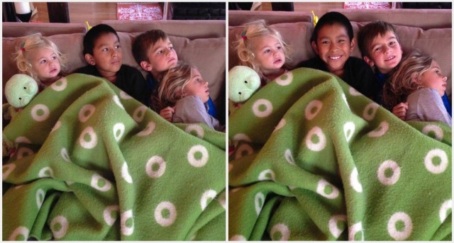 Kids snuggled under blanket