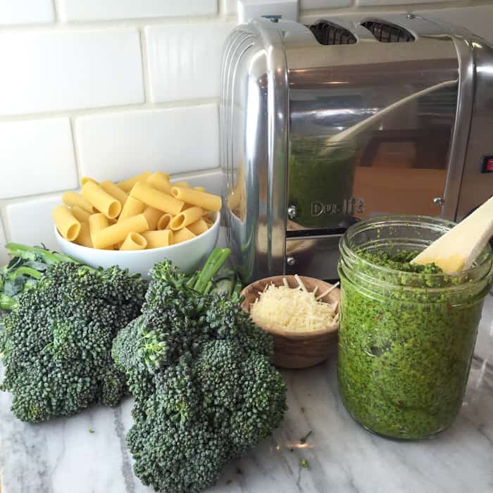 Pasta with pesto and broccolini in a jar on the counter with broccolini