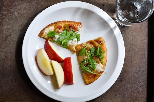 Pizza and sliced apples on plate