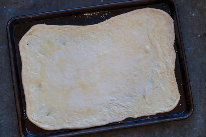 Pizza dough rolled out on the baking sheet