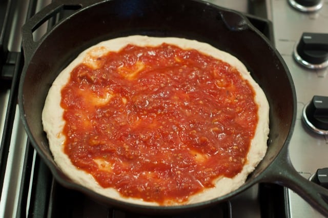 Sauced pizza dough in skillet