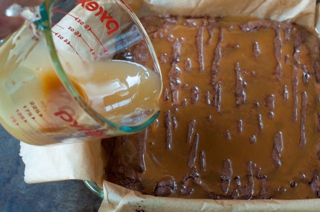 pouring caramel over baking brownies