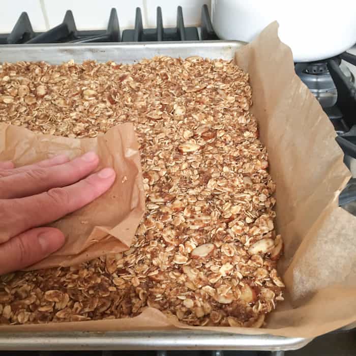 Pressing down the granola bark into the baking sheet