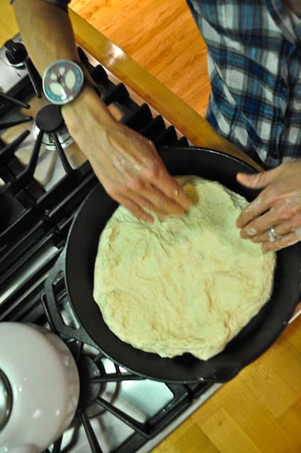 Pressing pizza dough into skillet