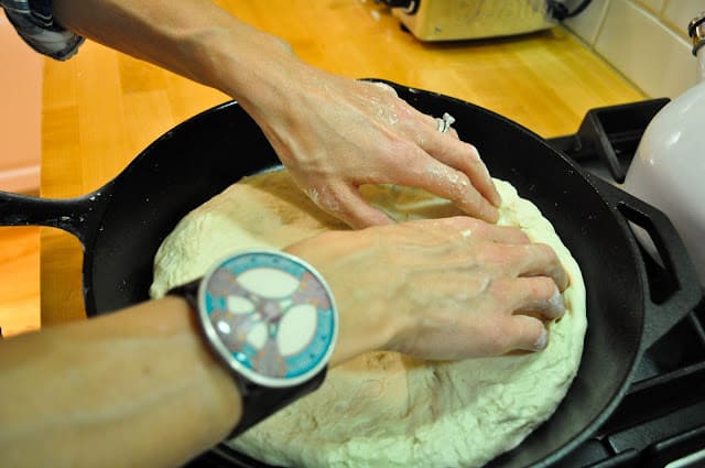 Pressing pizza dough into skillet