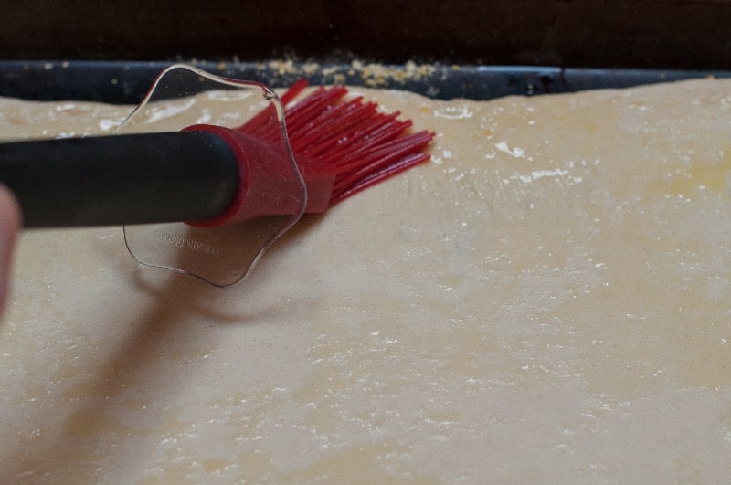 Pushing out the pizza dough to the edges of the baking sheet