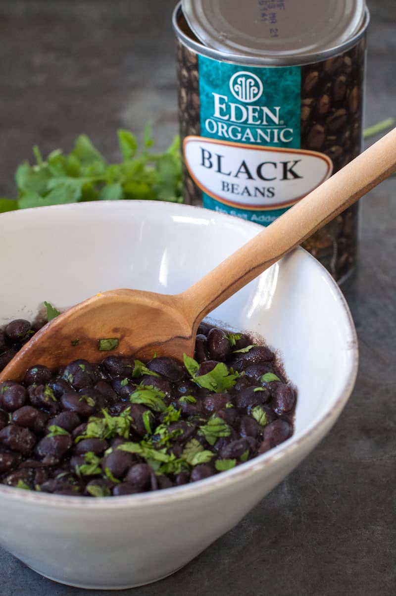 Quick and easy weeknight black beans in a white bowl with can of beans