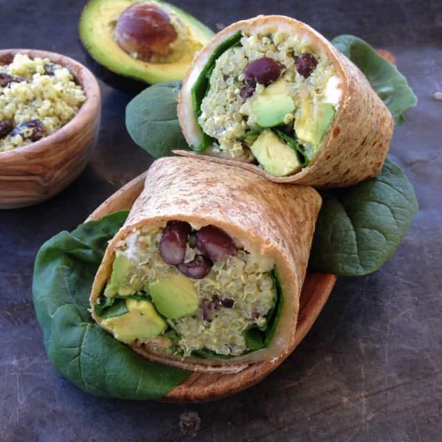 Quinoa wrap with black beans, feta, and avocado displayed on a table.
