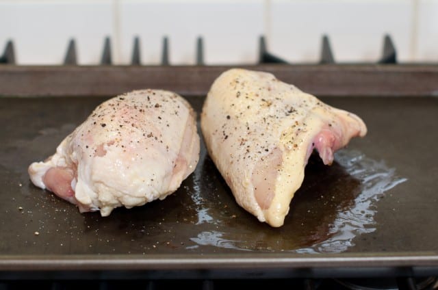 Raw chicken breasts that are ready for baking on a pan.