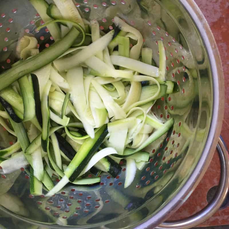 Raw Zucchini in strainer with sea salt