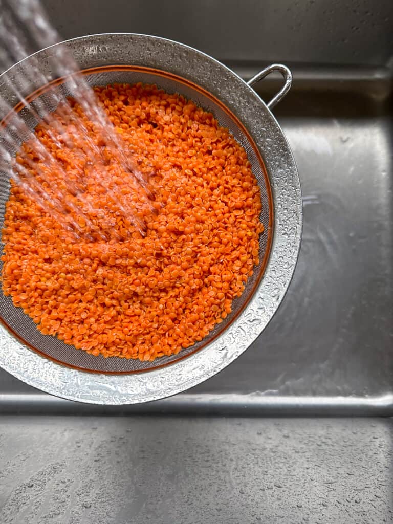 Rinsing red lentils with a fine mesh strainer.