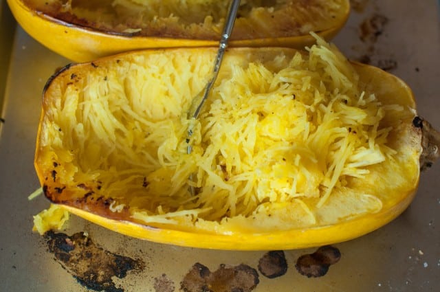 Scooping out cooked spaghetti squash