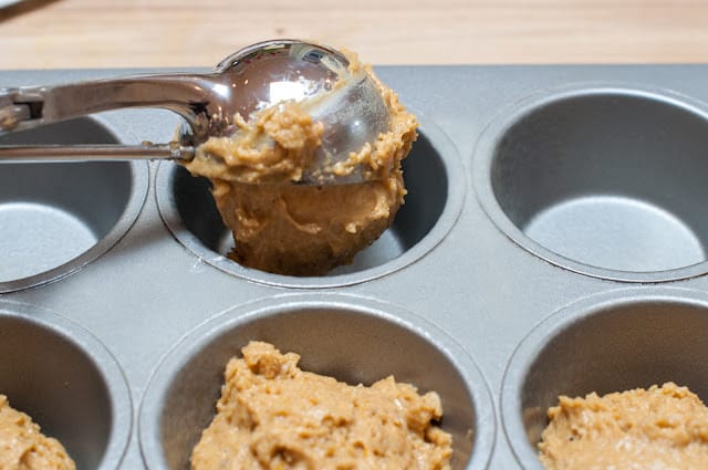 Scooping pumpkin muffins into muffin tin