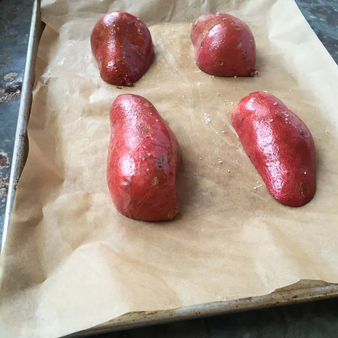 Sweet potatoes face down on baking sheet