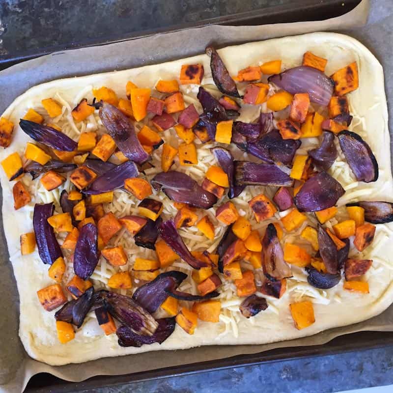 Topping the pizza with the fall roasted vegetables
