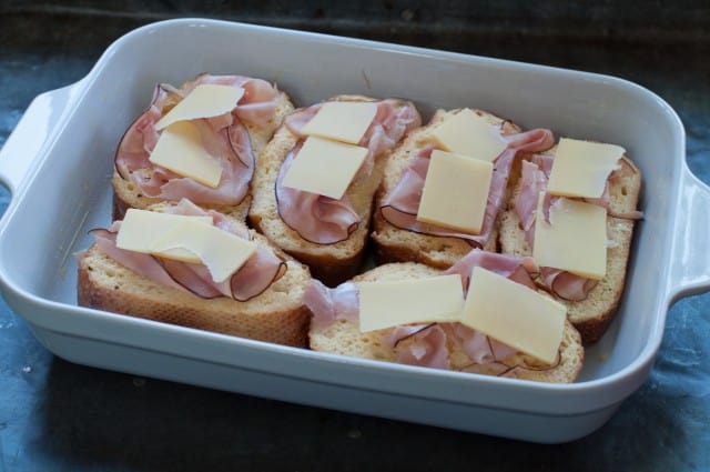 topping the stuffed toast with ham and cheese