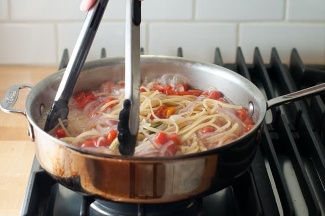 tossing pasta in a pot