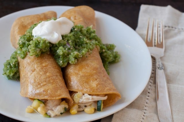 two chicken enchiladas with green sauce on a plate