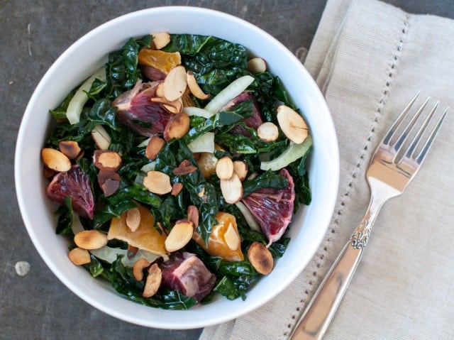 Vegan kale salad with citrus dressing in a bowl and fork