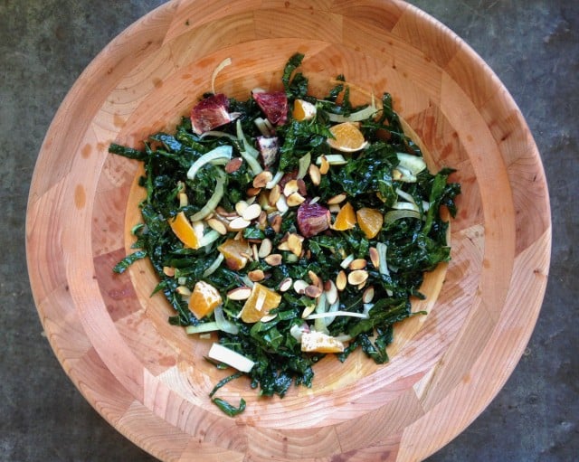 Vegan kale salad with citrus dressing in wooden bowl